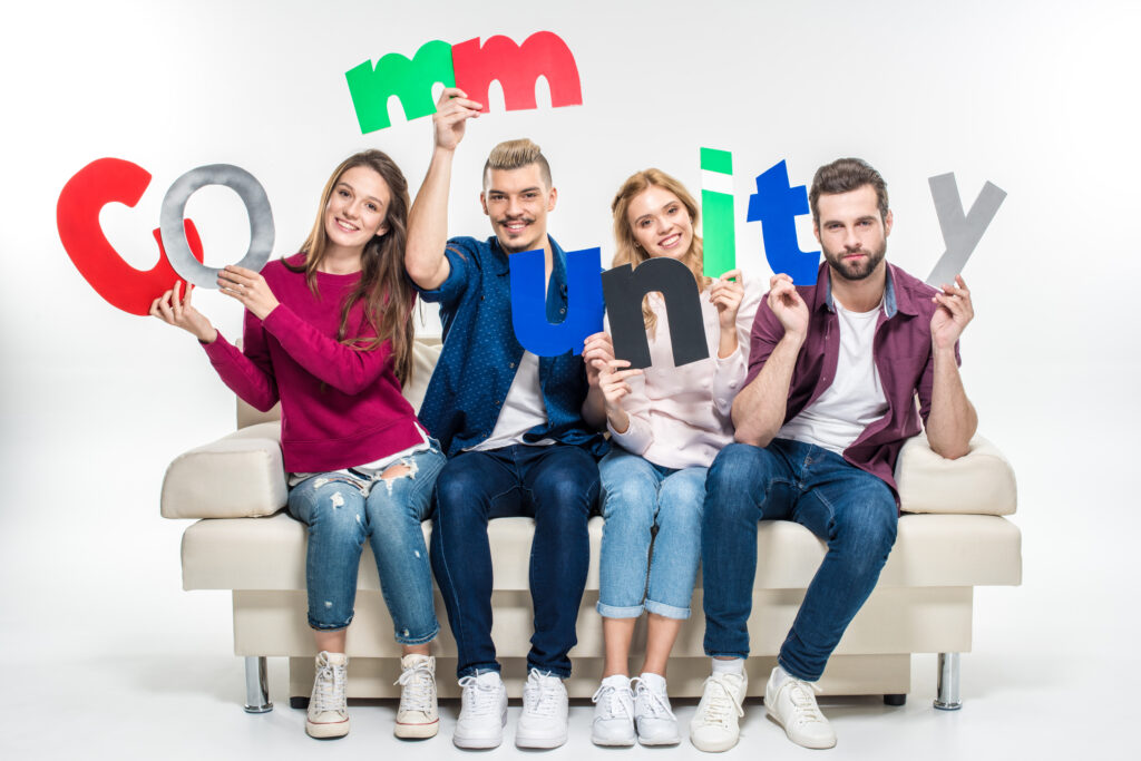 Several people sitting on a couch holding letters spelling out "community"