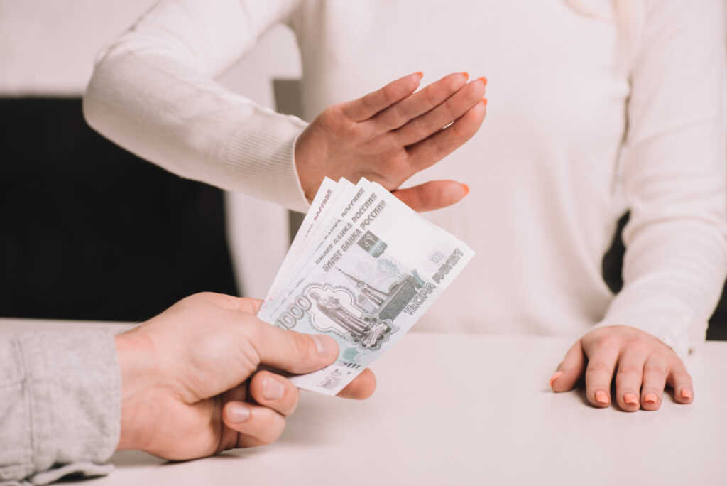 Woman’s hand rejecting paper money being handed over